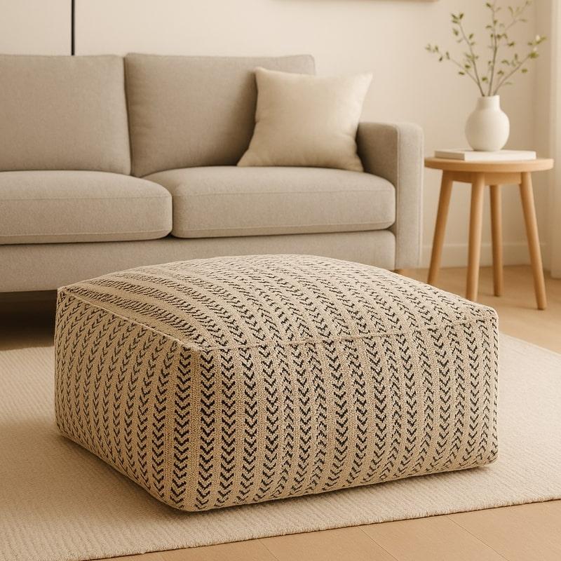 Handwoven cotton ottoman pouf with neutral-toned striped pattern, perfect for modern boho decor.