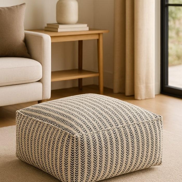 Handwoven cotton ottoman pouf with a neutral-toned striped weave pattern, perfect for modern boho decor.