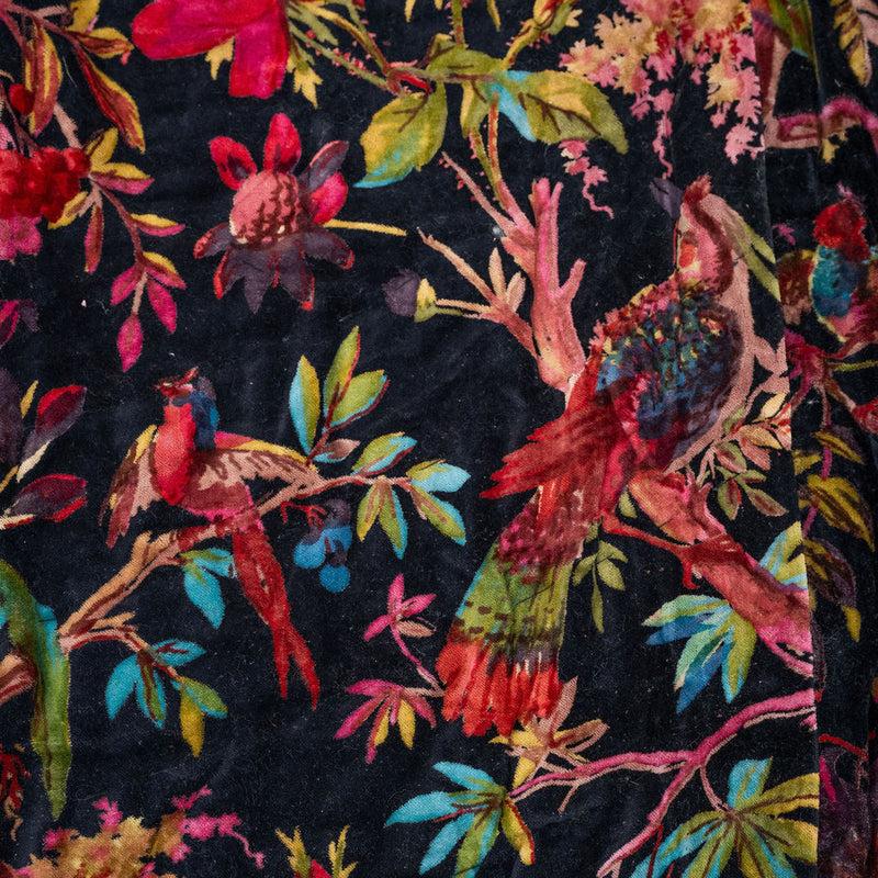 Close-up of a dark cotton velvet quilt with vibrant violet, fuchsia, teal, and emerald bird and botanical patterns.