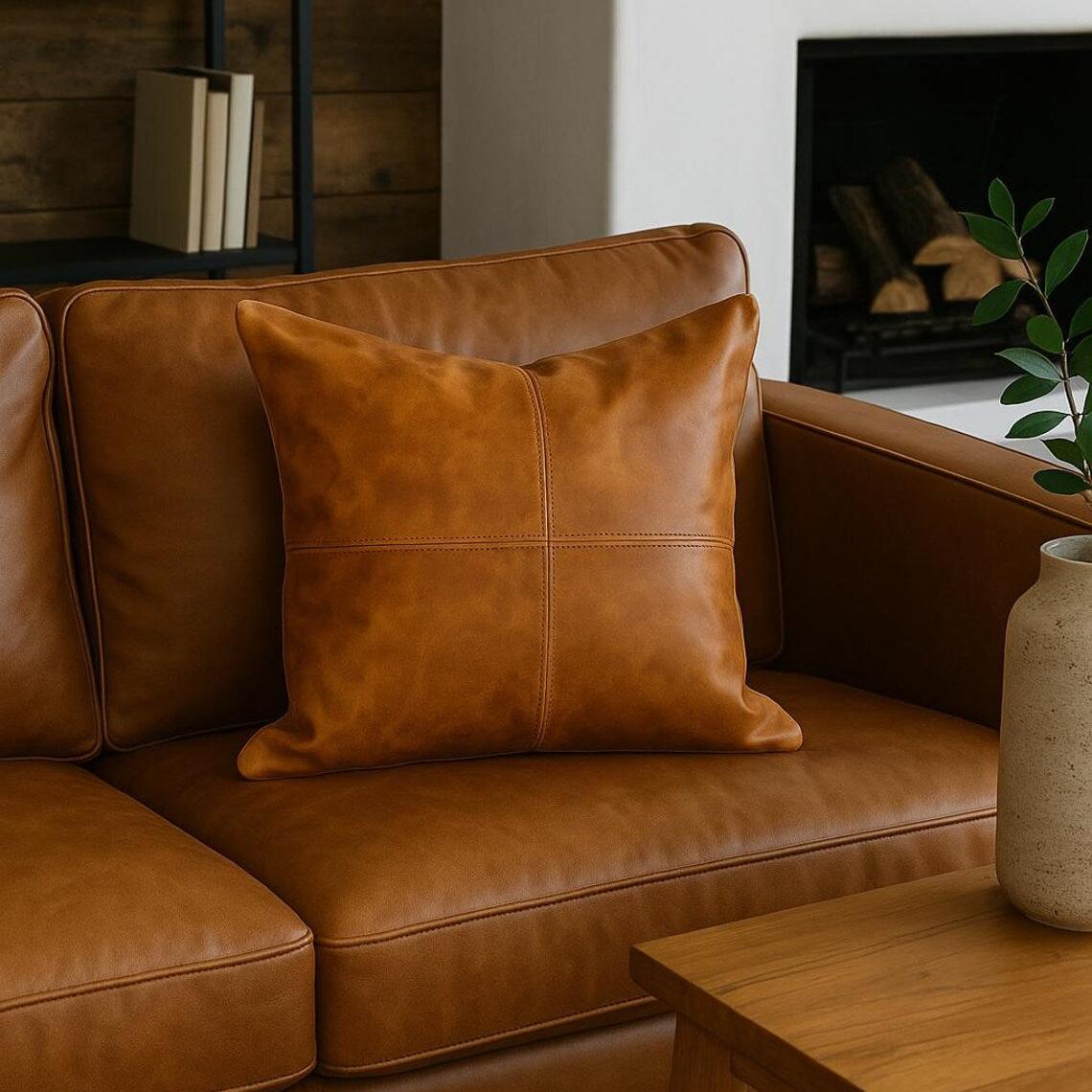 Tan leather cushion cover with stitched quadrants on a brown leather sofa.
