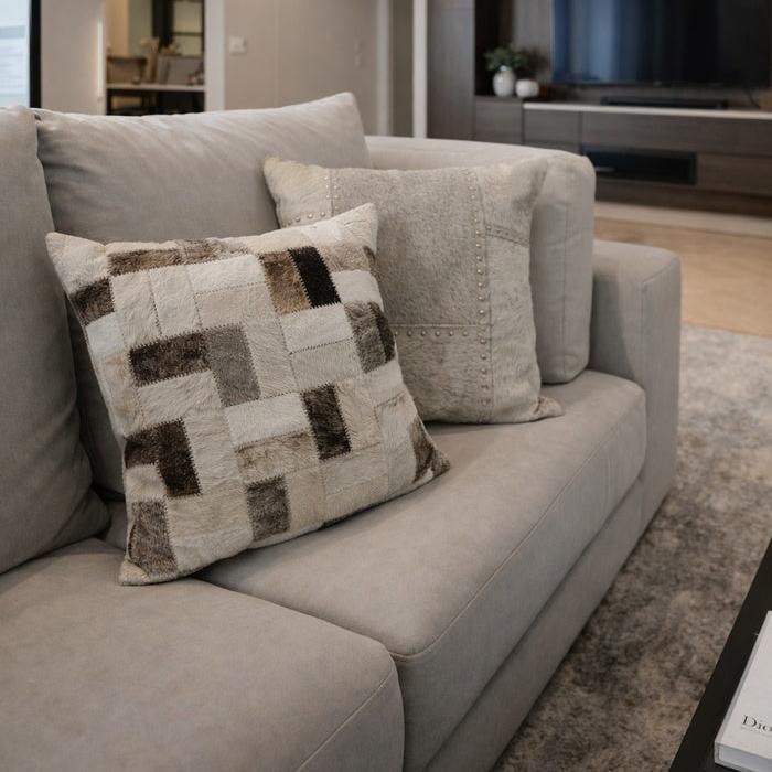 Neutral cowhide leather checkerboard cushion cover (45x45cm) on a light gray sofa.