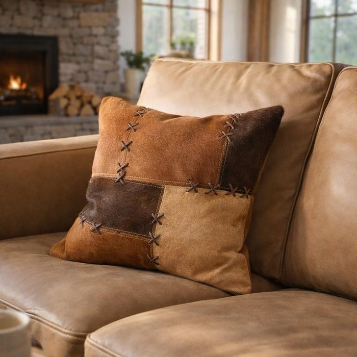 Handcrafted 45x45cm cowhide leather cushion cover with tan, caramel, and chocolate patchwork, featuring cross-stitch lacing.