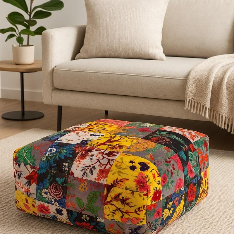 Boho velvet patchwork ottoman with colorful floral and bird patterns, square shape, on a rug in a living room.