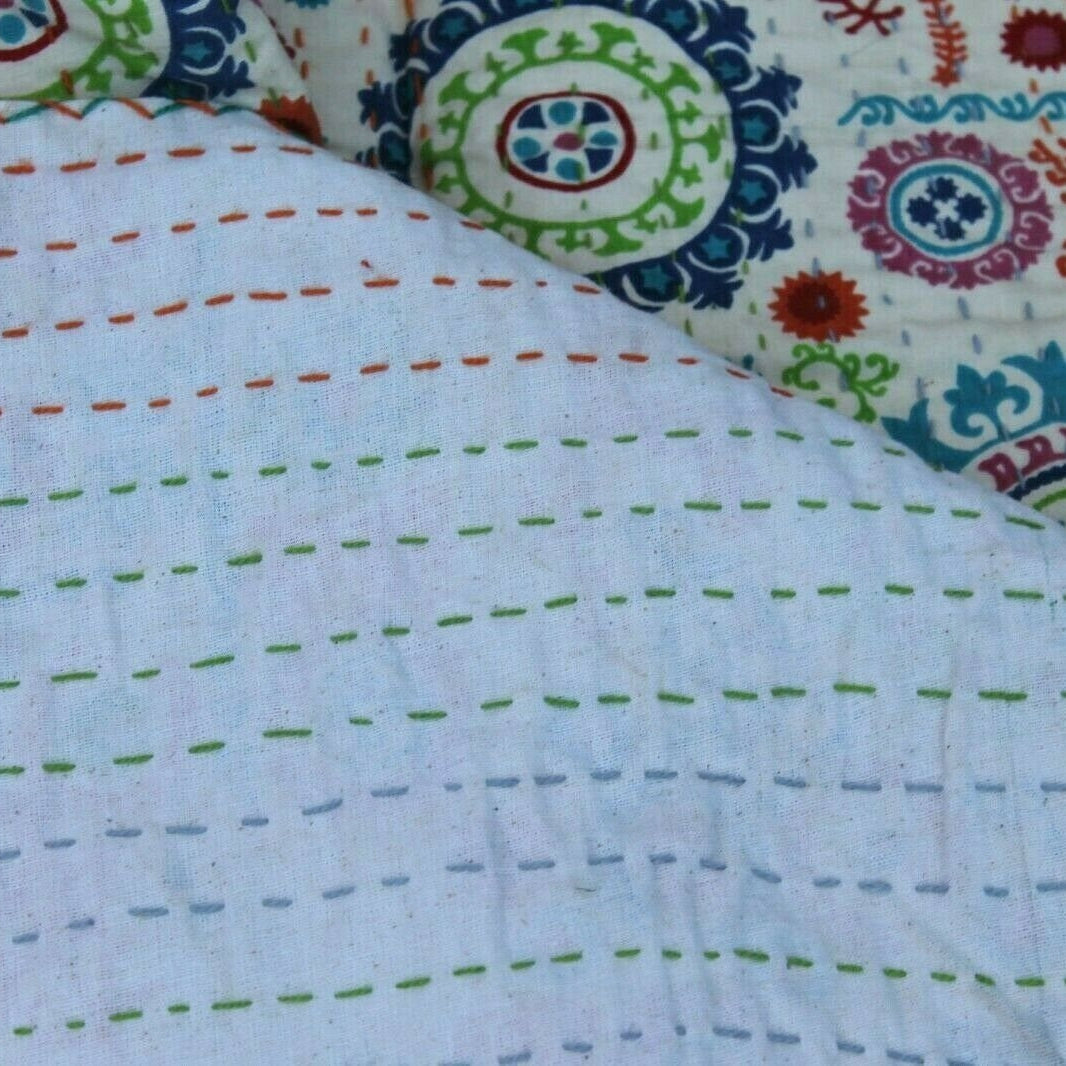 Reversible cotton Kantha quilt with colorful circular patterns on one side and hand-stitched lines on the other.