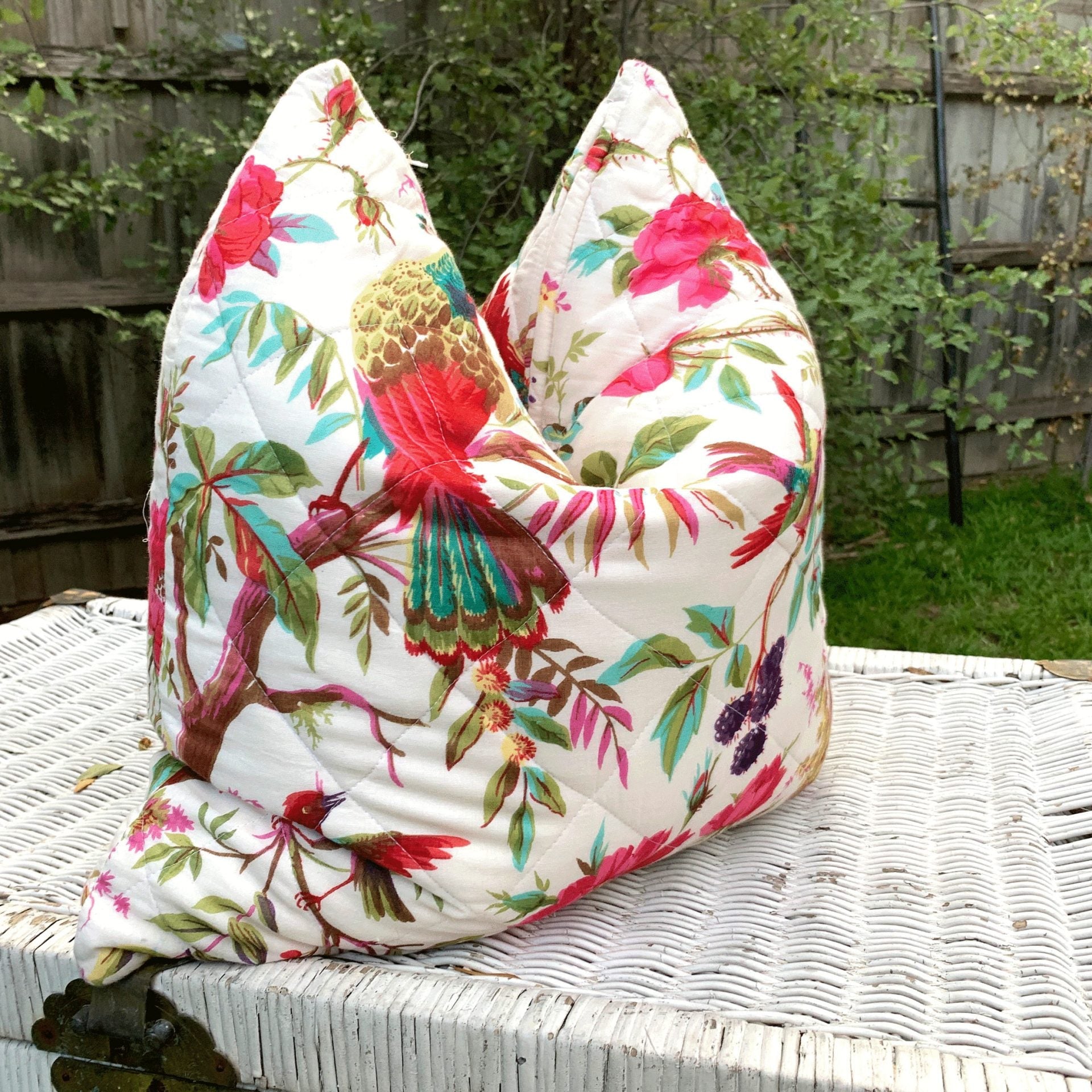 Handmade quilted white cotton cushion cover with vibrant floral and bird of paradise design.