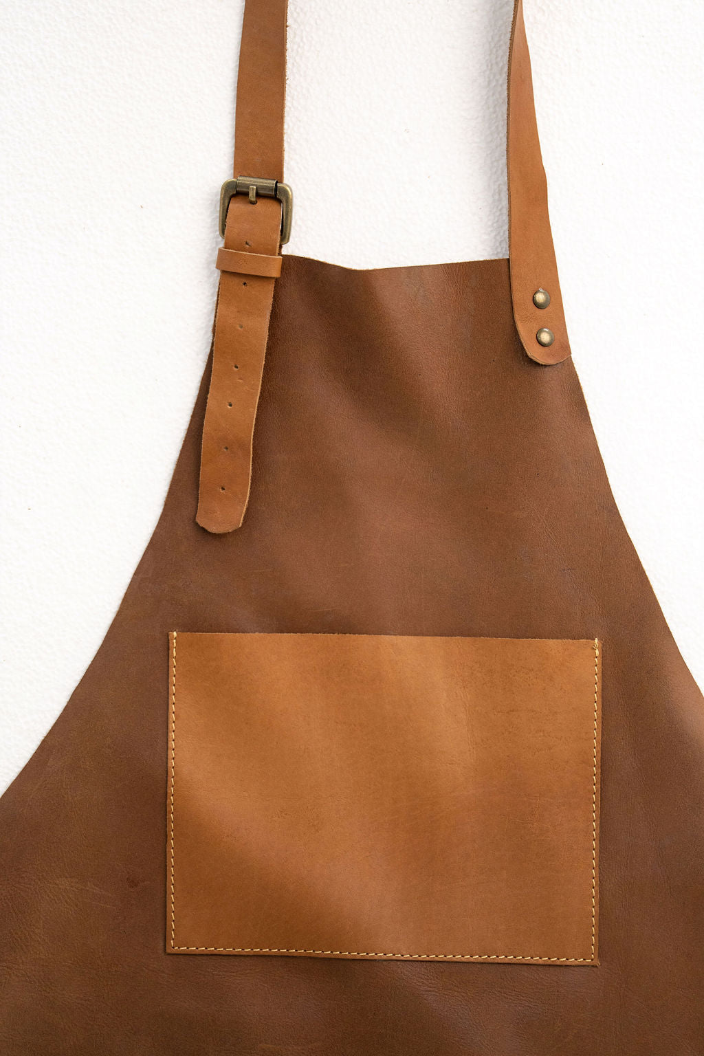 Adjustable tan leather apron with pockets for crafting and workshop