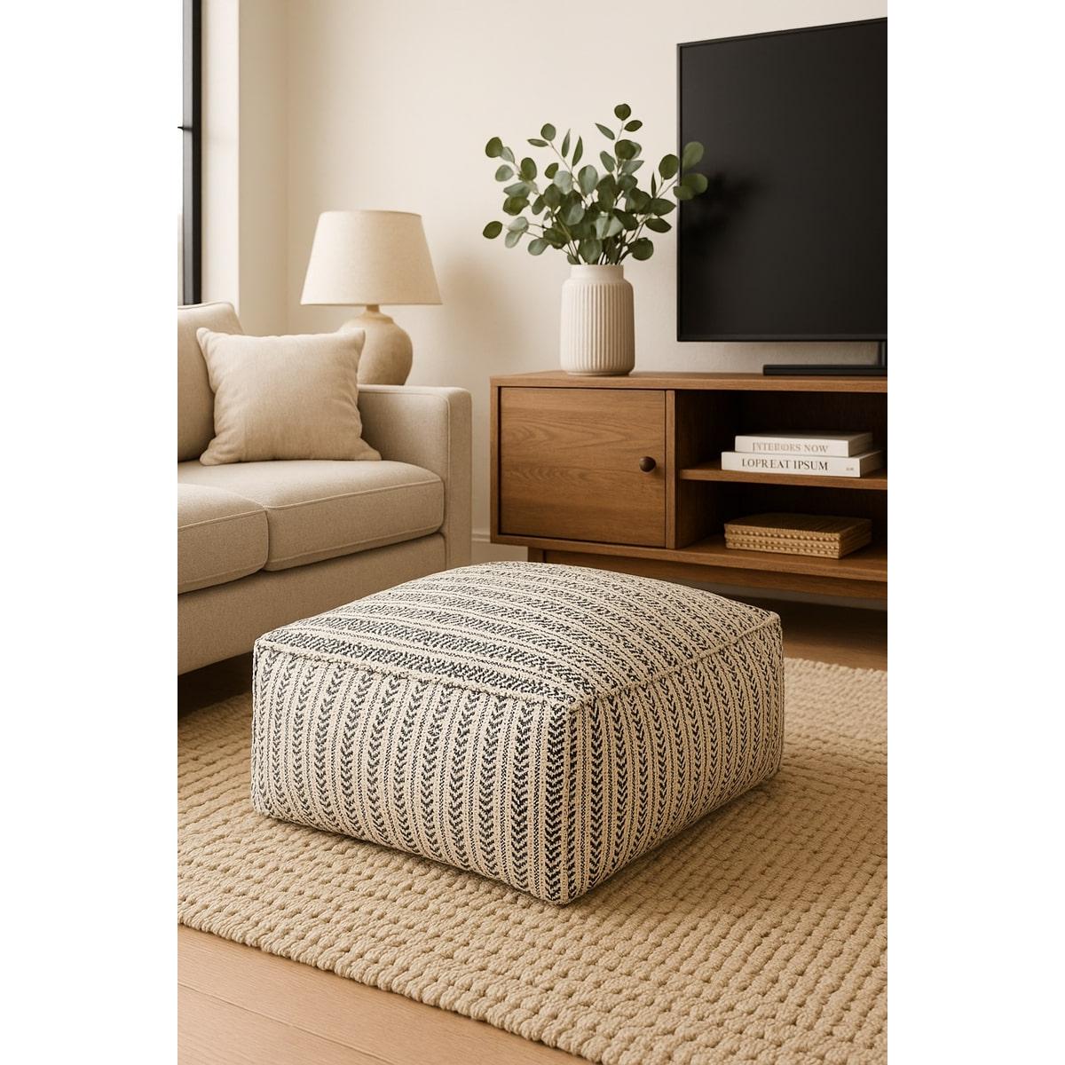 Handwoven cotton ottoman pouf with black and natural striped leaf pattern in a modern living room.