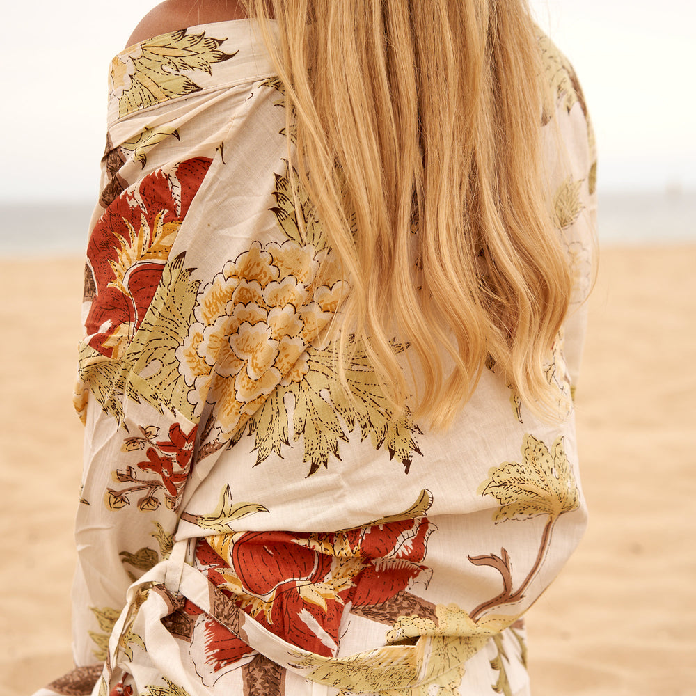 Woman from behind wearing a cream cotton kimono with earthy red and yellow floral print.