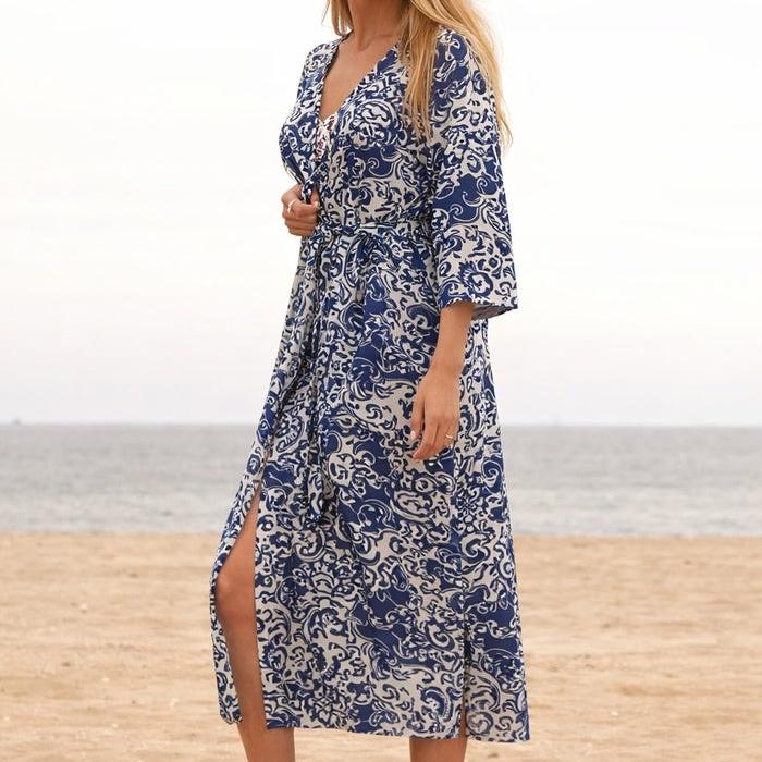 Woman wearing a free-size indigo and white cotton kimono robe with a bird of paradise print, tied at the waist, on a beach.