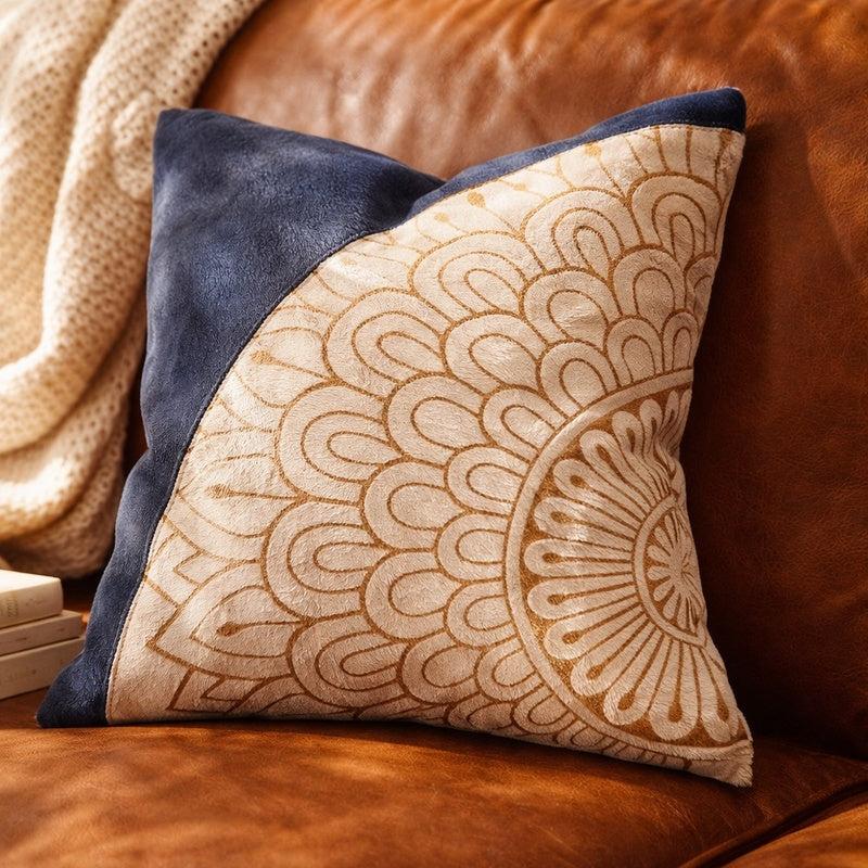 Blue & cream mandala cowhide leather cushion cover with a navy panel on a brown leather sofa.