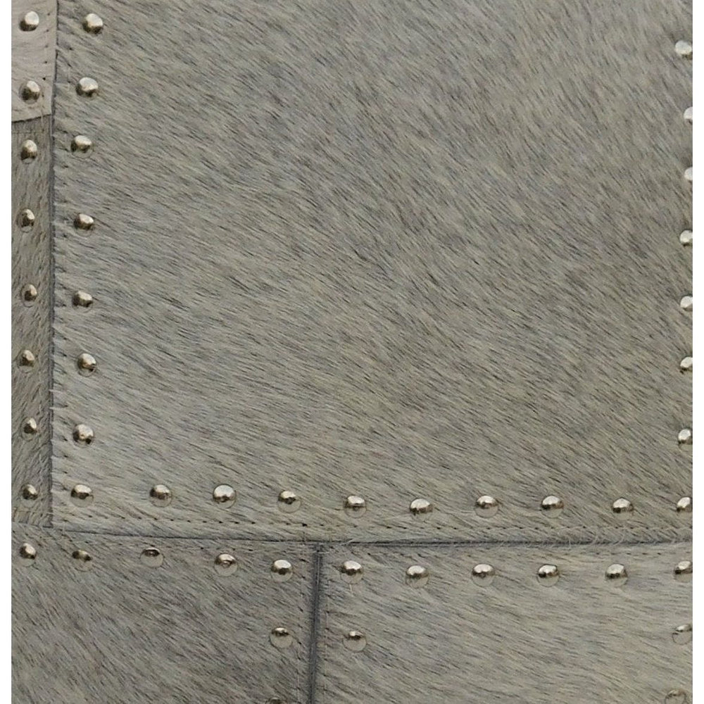 Gray cowhide leather cushion cover with patchwork panels and silver studded detailing.