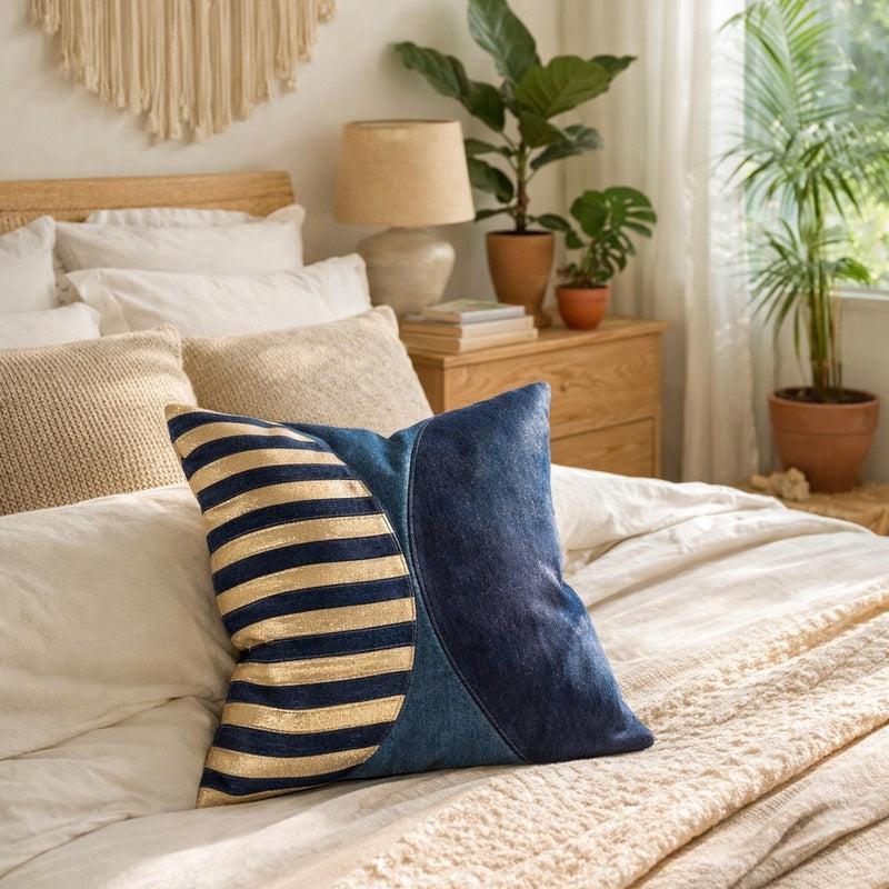 Handmade navy and metallic-silver striped cowhide cushion cover with a curved panel design on a bed.