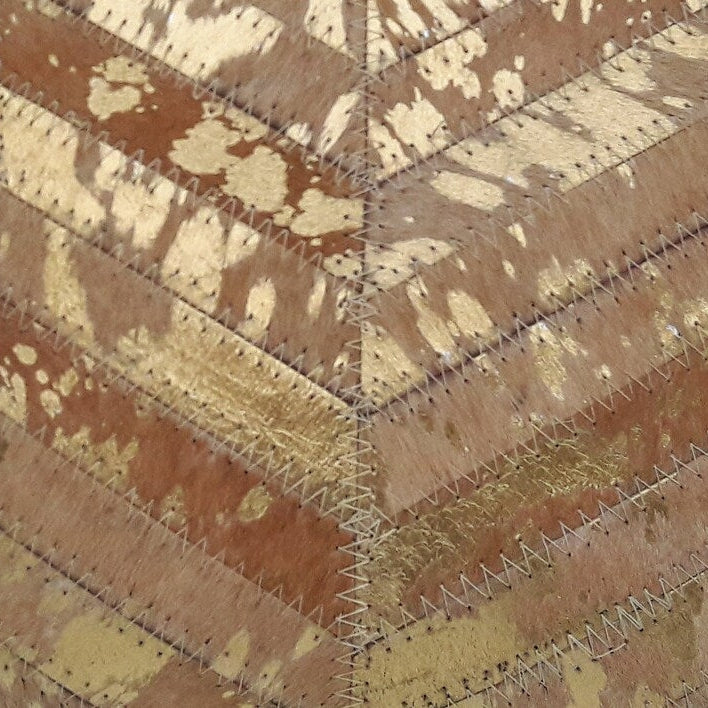 Golden exotic cowhide cushion cover with brown and gold patchwork chevron design.