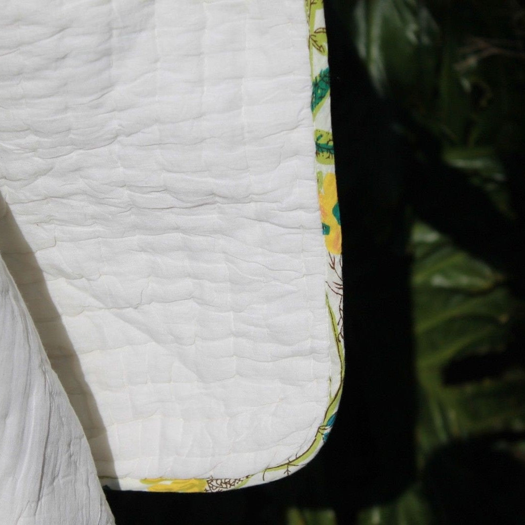 White quilted cotton Kantha blanket with a yellow and green floral border, showcasing hand-stitched detail.