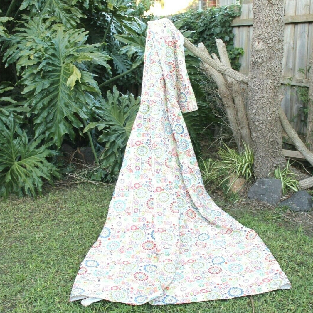 Colorful circles Kantha quilt, handcrafted 100% cotton, draped outdoors on grass.